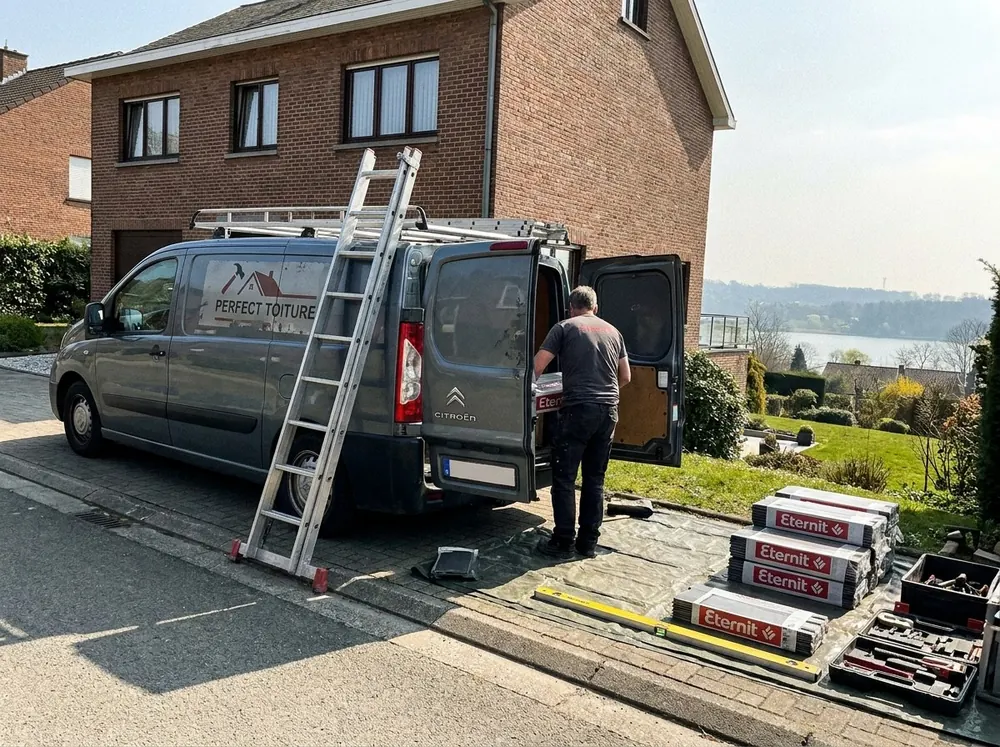 Utilitaire Perfect Toiture, échelle et paquets de tuiles devant une maison